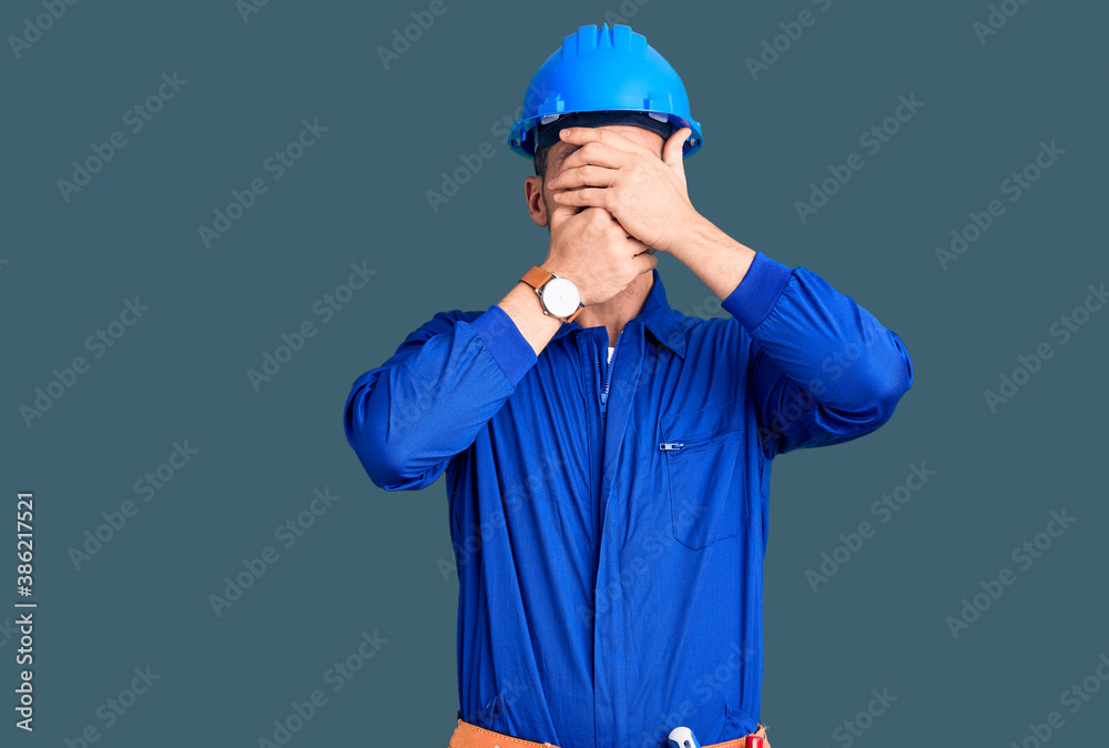 Young handsome man wearing worker uniform and hardhat rejection expression crossing arms and palms doing negative sign, angry face