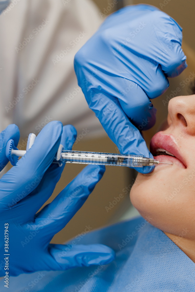 Lips augmentation injections for attractive girl. Plastic surgeon does injection in lip in medical clinic. Cosmetic rejuvenating facial treatment. Lips augmentation injections for attractive girl. Plastic surgeon does injection in lip in medical clinic. Cosmetic rejuvenating facial treatment.