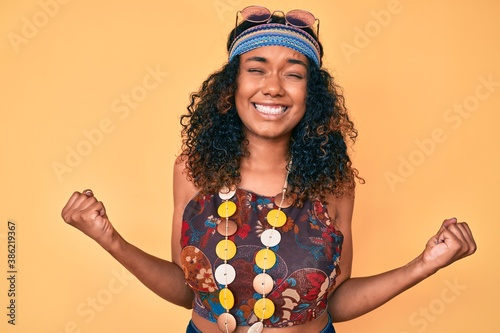 Young african american woman wearing bohemian and hippie style very happy and excited doing winner gesture with arms raised, smiling and screaming for success. celebration concept. photo