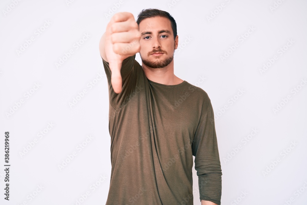 Young handsome man wearing casual clothes looking unhappy and angry showing rejection and negative with thumbs down gesture. bad expression. Young handsome man wearing casual clothes looking unhappy and angry showing rejection and negative with thumbs down gesture. bad expression.