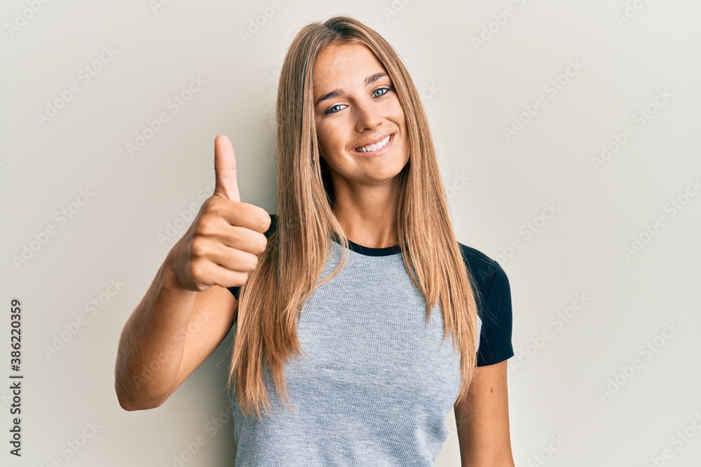 Young blonde woman wearing casual clothes smiling happy and positive, thumb up doing excellent and approval sign Young blonde woman wearing casual clothes smiling happy and positive, thumb up doing excellent and approval sign