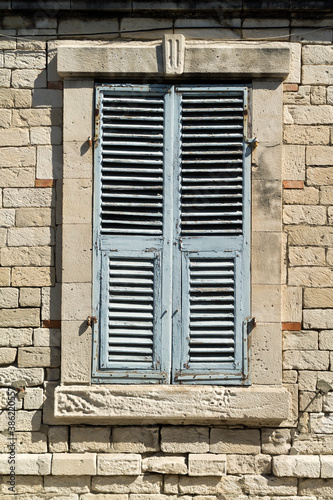 Old window with wooden shutters in brick wall 