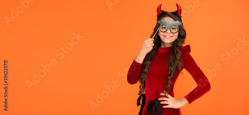 smiling cheerful child in imp horn costume to halloween with bat party glasses, happy halloween, copy space