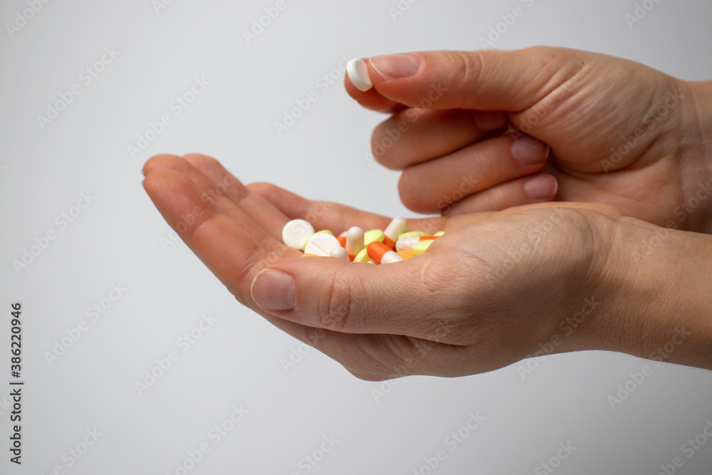 Colored painkillers in the palms and white pill in fingers Colored painkillers in the palms and white pill in fingers