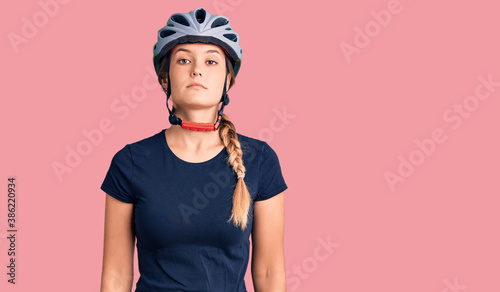 Beautiful caucasian woman wearing bike helmet relaxed with serious expression on face. simple and natural looking at the camera.