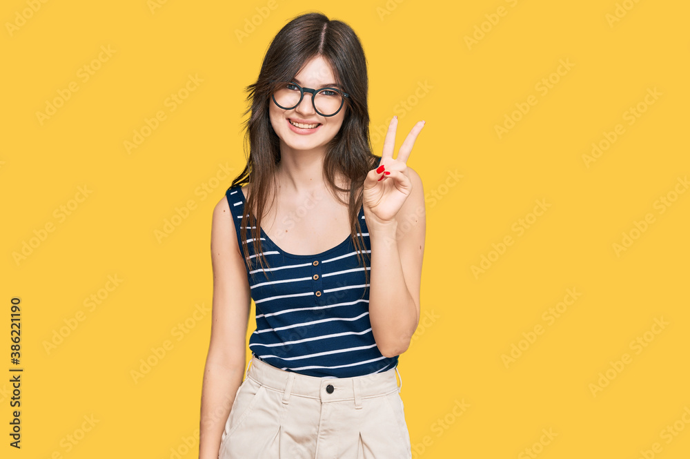 Young beautiful caucasian girl wearing casual clothes and glasses showing and pointing up with fingers number two while smiling confident and happy. Young beautiful caucasian girl wearing casual clothes and glasses showing and pointing up with fingers number two while smiling confident and happy.