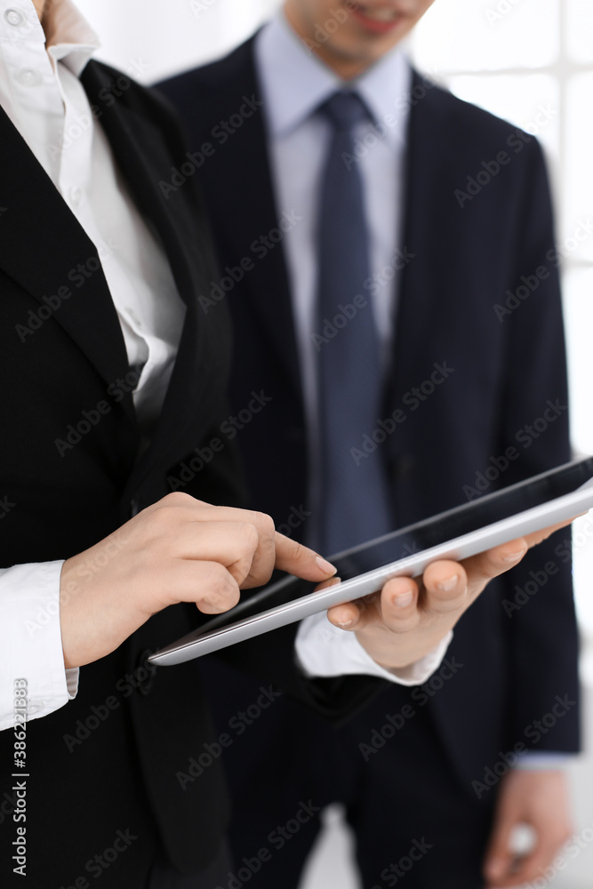 Businessman and woman using tablet computer for discussing questions in office. Partners or colleagues at meeting. Business cooperation concept Businessman and woman using tablet computer for discussing questions in office. Partners or colleagues at meeting. Business cooperation concept