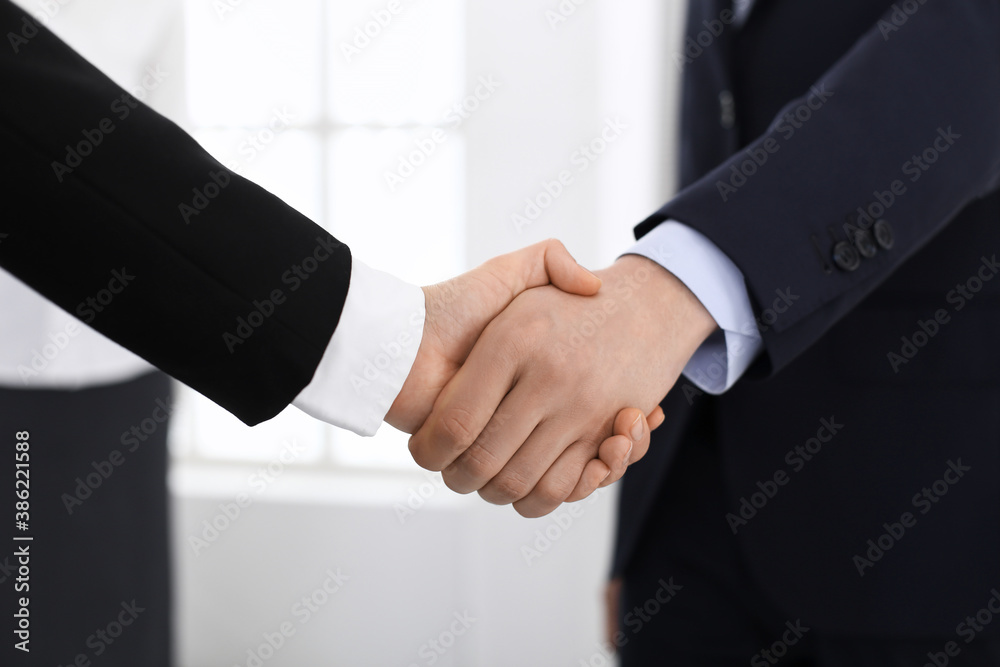 Businessman and woman shaking hands with colleagues at the background. Handshake at meeting in office. Concept of success in business Businessman and woman shaking hands with colleagues at the background. Handshake at meeting in office. Concept of success in business