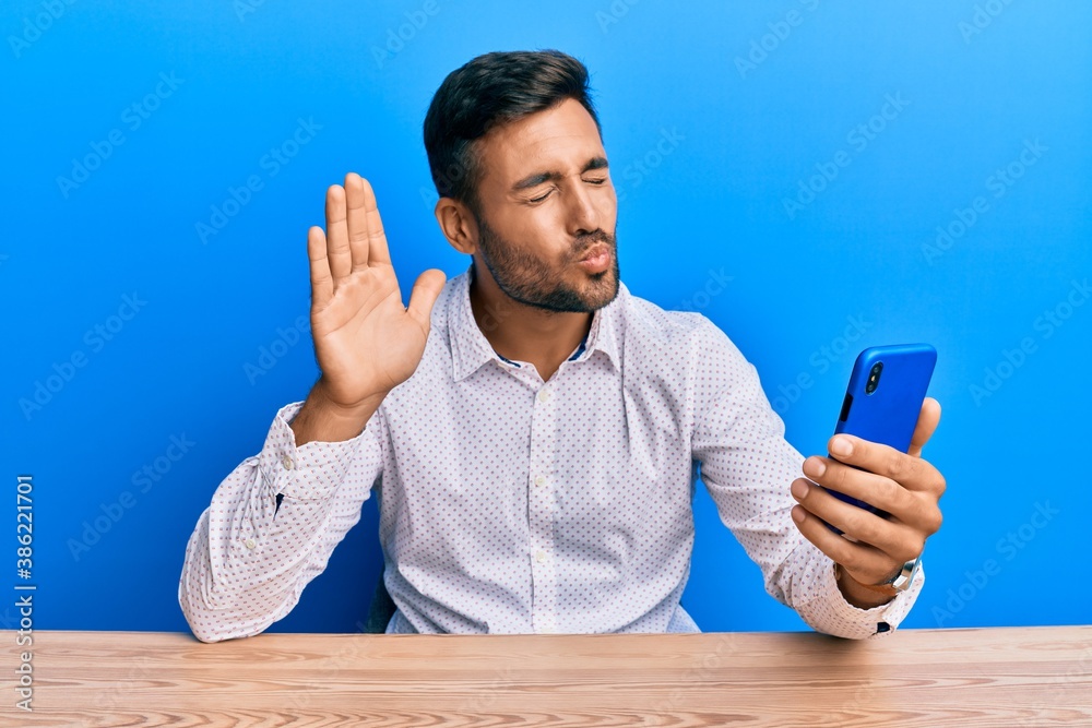 Handsome hispanic man doing video call waving to smartphone looking at the  camera blowing a kiss being lovely and sexy. love expression. Stock Photo |  Adobe Stock