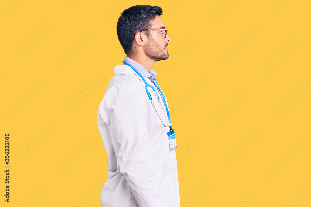 Young hispanic man wearing doctor uniform and stethoscope looking to side, relax profile pose with natural face and confident smile.