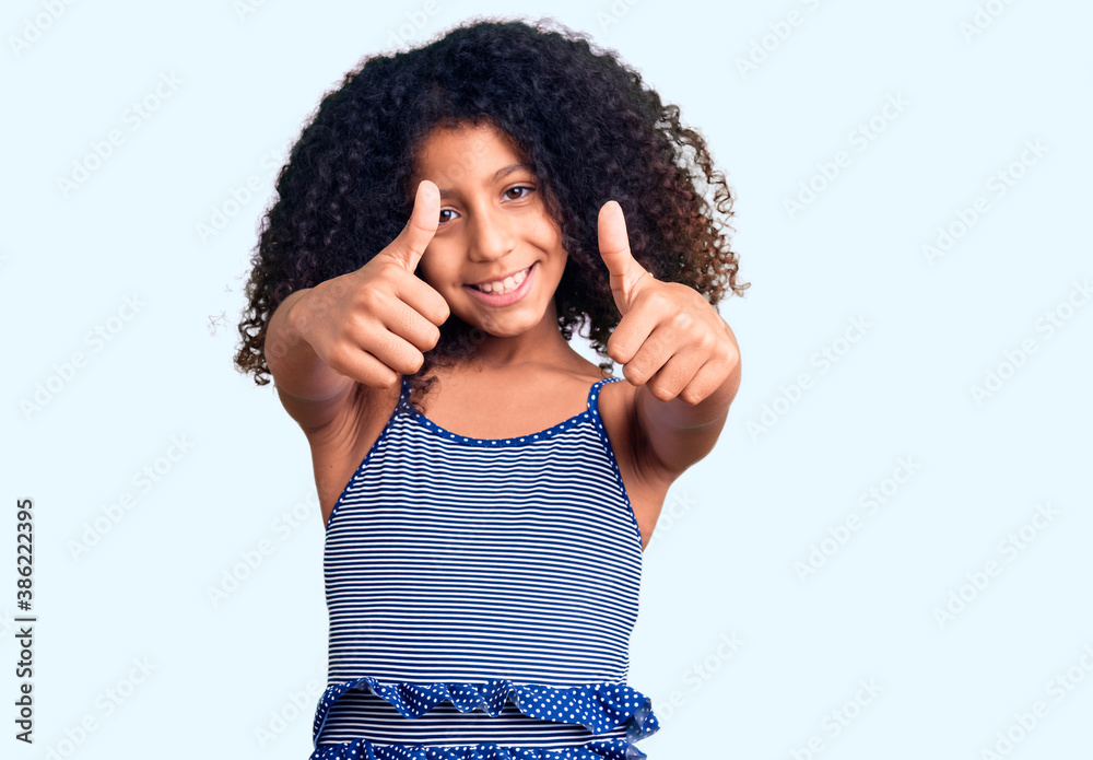 African american child with curly hair wearing swimwear approving doing positive gesture with hand, thumbs up smiling and happy for success. winner gesture. African american child with curly hair wearing swimwear approving doing positive gesture with hand, thumbs up smiling and happy for success. winner gesture.