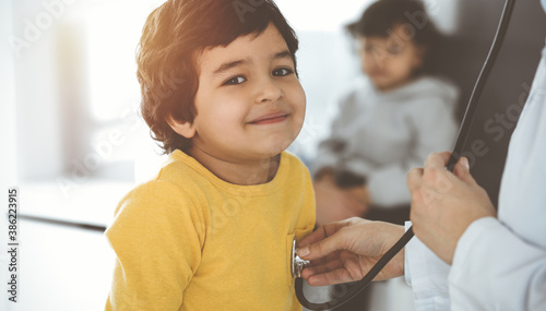 Valokuva Woman-doctor examining a child patient by stethoscope in sunny clinik
