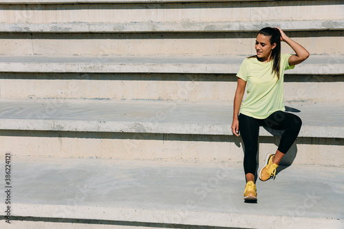 Fitness woman sitting on stairs and enjoying sunbeams.