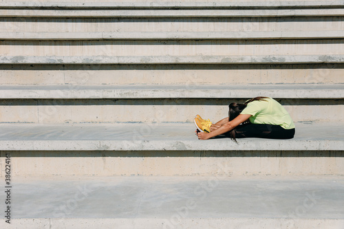 Flexible young woman stretching body on steps