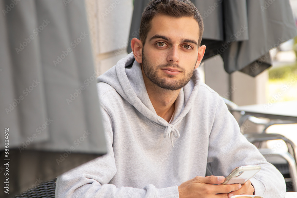Obraz premium young man with mobile phone sitting in cafe terrace