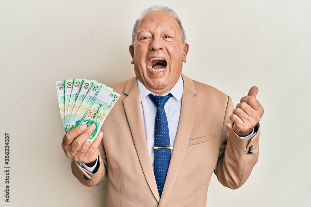 Senior caucasian man holding 50 hong kong dollars banknotes pointing thumb up to the side smiling happy with open mouth Senior caucasian man holding 50 hong kong dollars banknotes pointing thumb up to the side smiling happy with open mouth