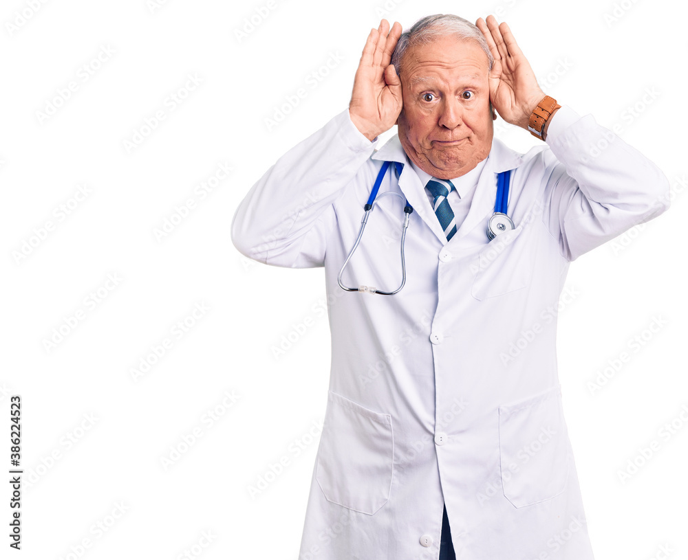 Senior handsome grey-haired man wearing doctor coat and stethoscope doing bunny ears gesture with hands palms looking cynical and skeptical. easter rabbit concept. Senior handsome grey-haired man wearing doctor coat and stethoscope doing bunny ears gesture with hands palms looking cynical and skeptical. easter rabbit concept.