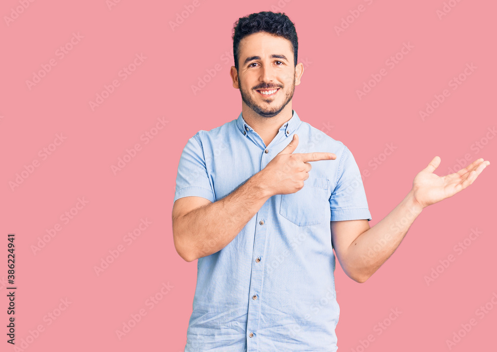 Young hispanic man wearing casual clothes amazed and smiling to the camera while presenting with hand and pointing with finger. Young hispanic man wearing casual clothes amazed and smiling to the camera while presenting with hand and pointing with finger.