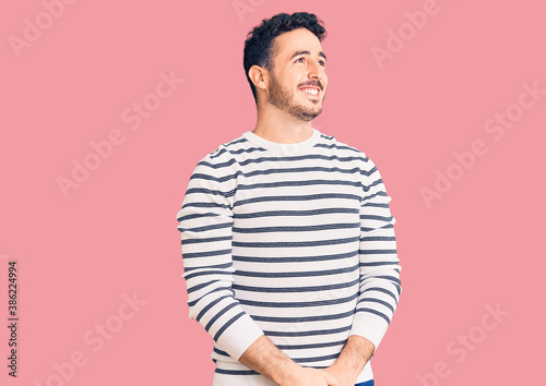 Wallpaper Mural Young hispanic man wearing casual clothes looking away to side with smile on face, natural expression. laughing confident. Torontodigital.ca