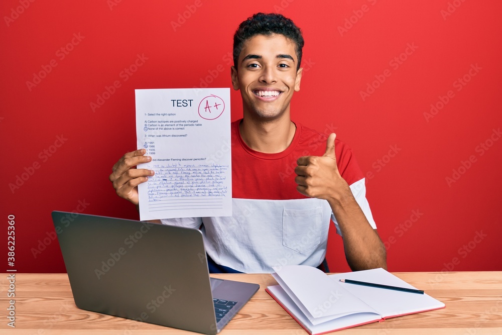 Young handsome african american man showing a passed exam smiling happy and positive, thumb up doing excellent and approval sign Young handsome african american man showing a passed exam smiling happy and positive, thumb up doing excellent and approval sign