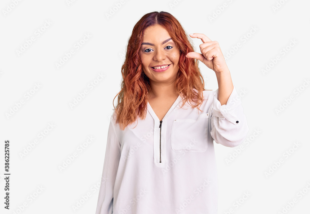 Young latin woman wearing casual clothes smiling and confident gesturing with hand doing small size sign with fingers looking and the camera. measure concept. Young latin woman wearing casual clothes smiling and confident gesturing with hand doing small size sign with fingers looking and the camera. measure concept.