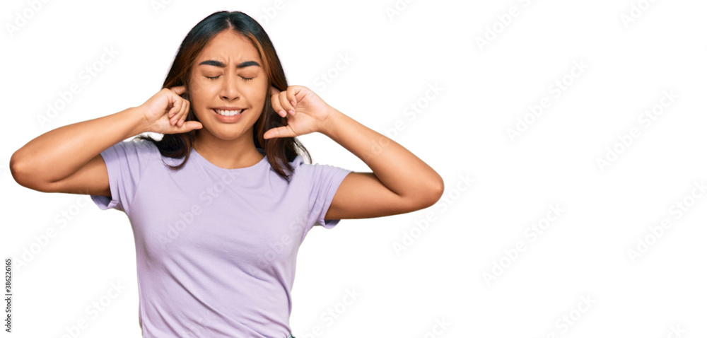 Young latin woman wearing casual clothes covering ears with fingers with annoyed expression for the noise of loud music. deaf concept. Young latin woman wearing casual clothes covering ears with fingers with annoyed expression for the noise of loud music. deaf concept.