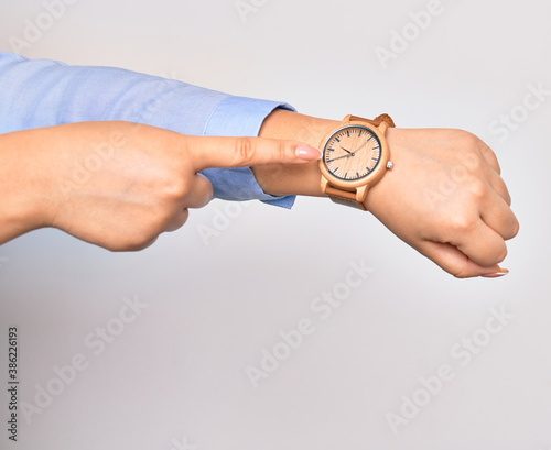 Hand of caucasian young businesswoman wearing wristwatch. Pointing with finger to watch over isolated white background