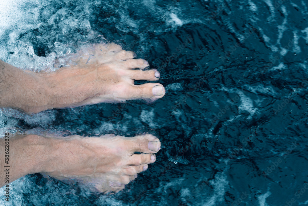 Fototapeta premium Male feet on black sand beach shore