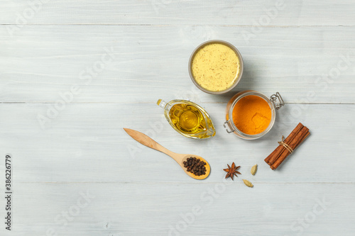 Golden milk, turmeric and spices for cooking on a light wooden background. top view with space
