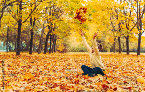 a boy sitting in an autumn Park and having fun with maple trees