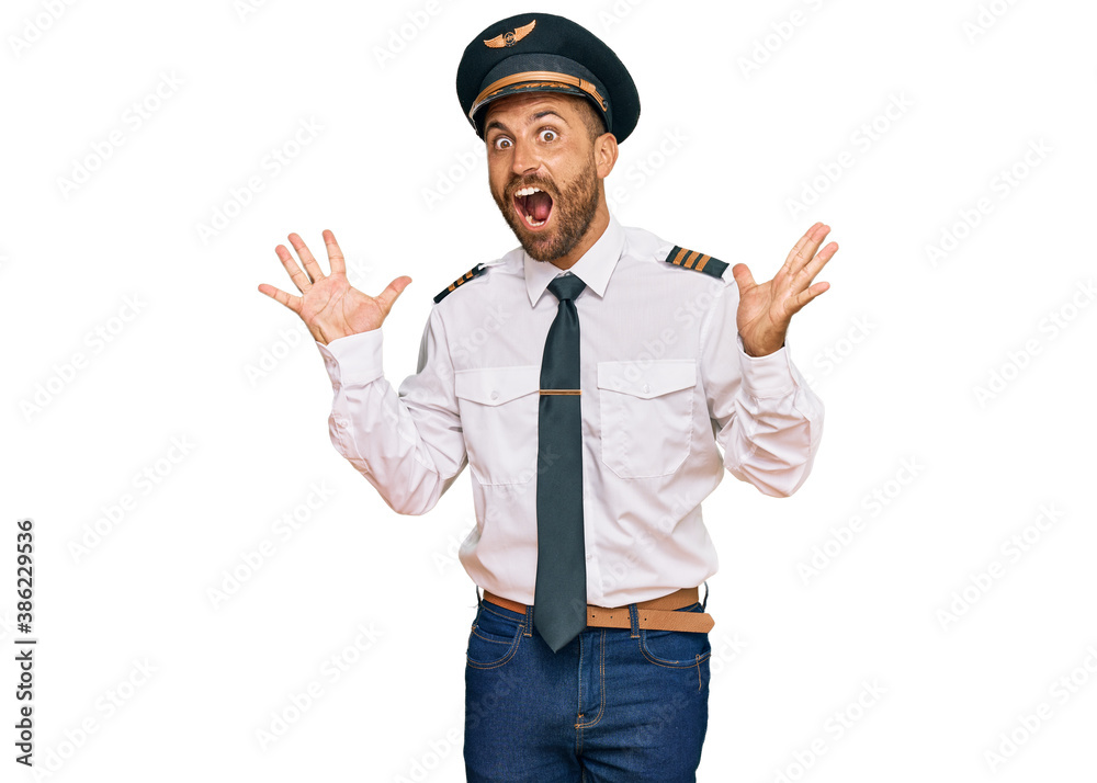 Handsome man with beard wearing airplane pilot uniform celebrating crazy and amazed for success with arms raised and open eyes screaming excited. winner concept Handsome man with beard wearing airplane pilot uniform celebrating crazy and amazed for success with arms raised and open eyes screaming excited. winner concept