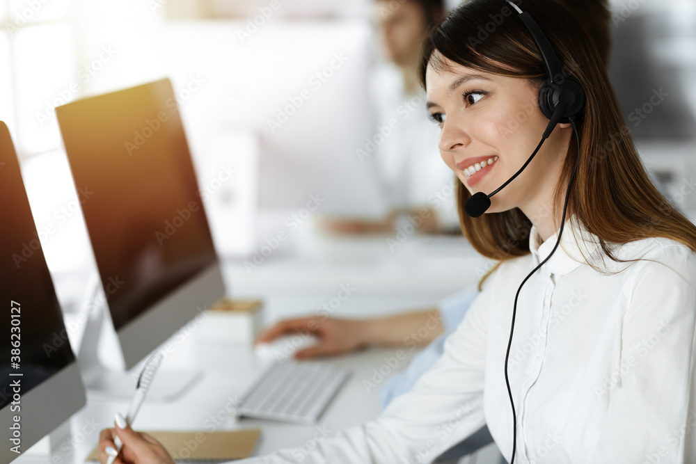 Asian woman working at customer service office. Business concept. Group of diverse operators at work in sunny call center. Asian woman working at customer service office. Business concept. Group of diverse operators at work in sunny call center.