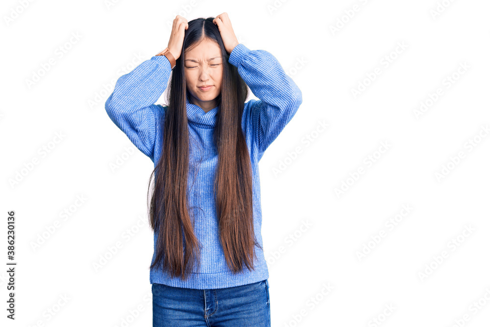 Young beautiful chinese woman wearing casual turtleneck sweater suffering from headache desperate and stressed because pain and migraine. hands on head. Young beautiful chinese woman wearing casual turtleneck sweater suffering from headache desperate and stressed because pain and migraine. hands on head.