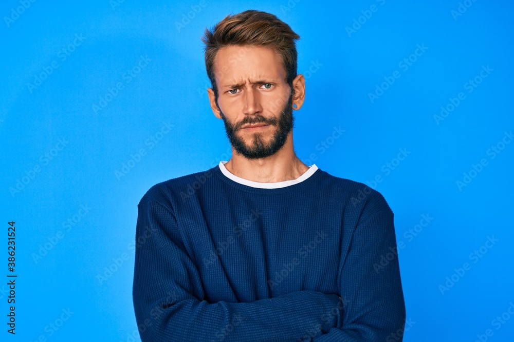 Handsome caucasian man with beard wearing casual sweater skeptic and nervous, disapproving expression on face with crossed arms. negative person. Handsome caucasian man with beard wearing casual sweater skeptic and nervous, disapproving expression on face with crossed arms. negative person.