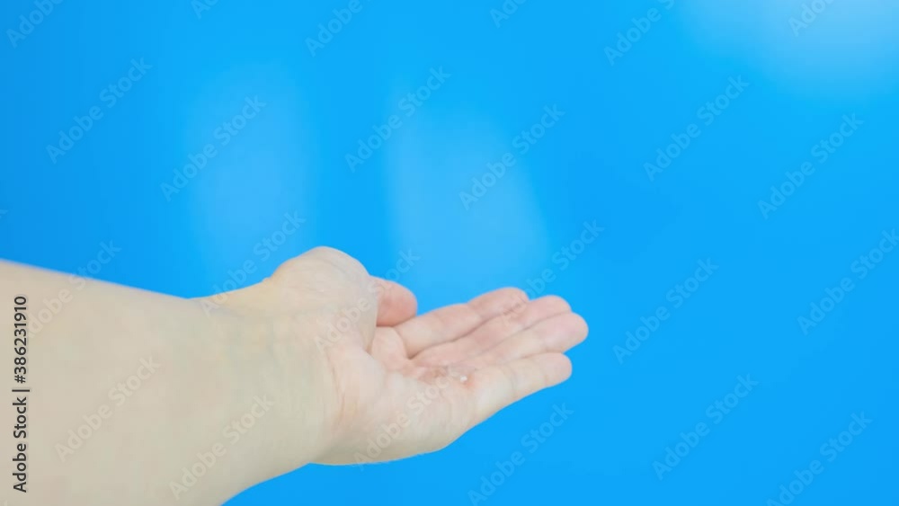 Hands using sanitizer gel in pump dispenser against blue background Hands using sanitizer gel in pump dispenser against blue background