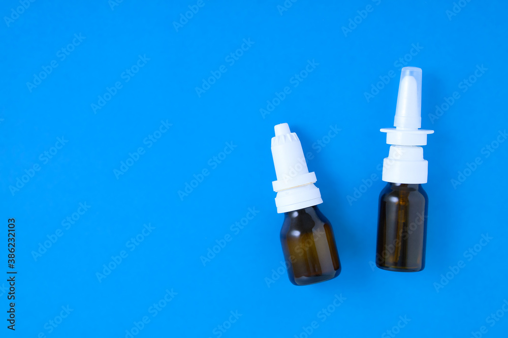Two brown glass bottles with drops for the nose eyes close-up. Blue background. Two brown glass bottles with drops for the nose eyes close-up. Blue background.