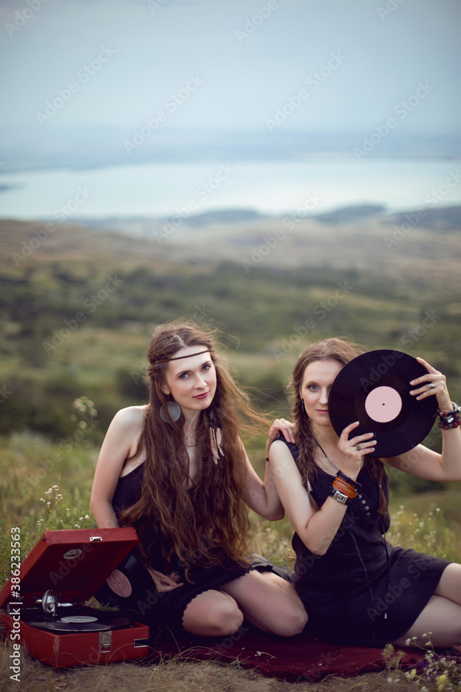 two hippie woman are lying in a field on a mountain