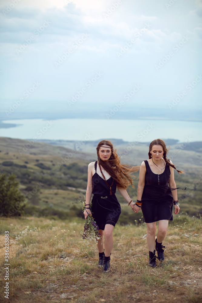 two woman in black dresses walk on the mountain with a bouquet two woman in black dresses walk on the mountain with a bouquet