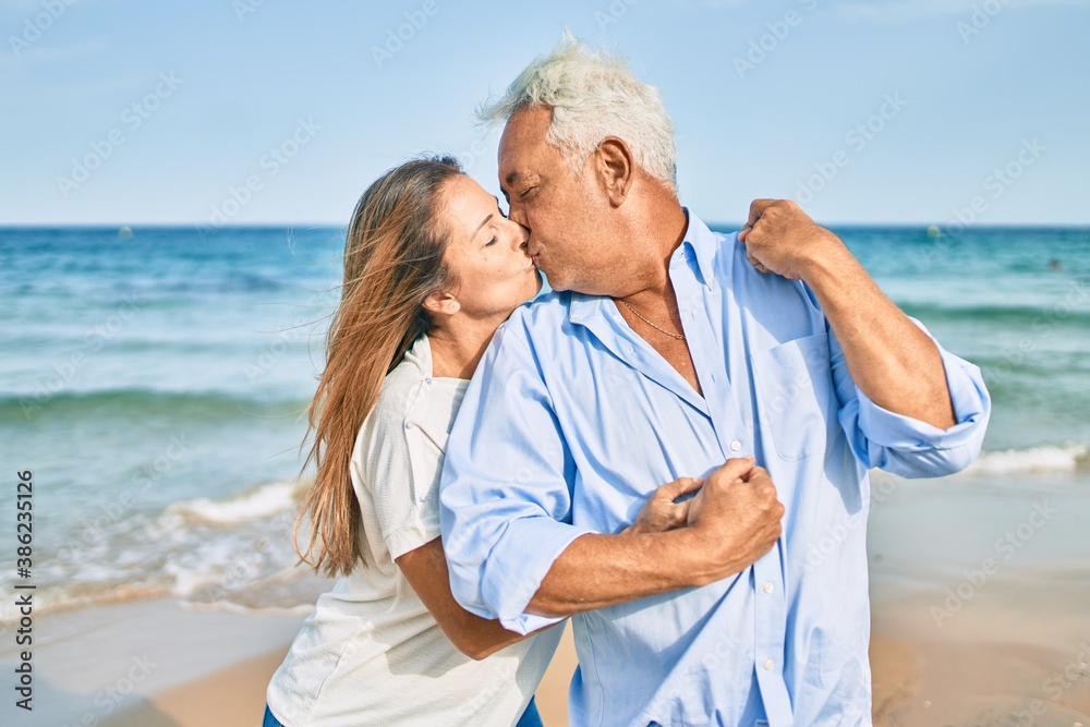 Middle age hispanic couple smiling happy and hugging walking at the beach Middle age hispanic couple smiling happy and hugging walking at the beach