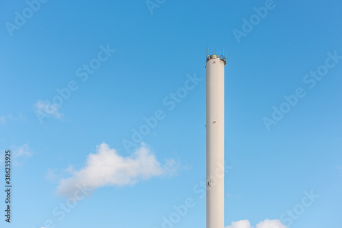 Tall white chimney on a blue sky.