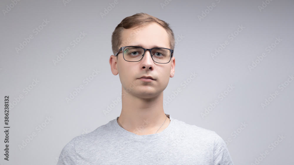 Close-up portrait of a business man with glasses, looking at the camera with a serious face, isolated on a white-gray background Close-up portrait of a business man with glasses, looking at the camera with a serious face, isolated on a white-gray background