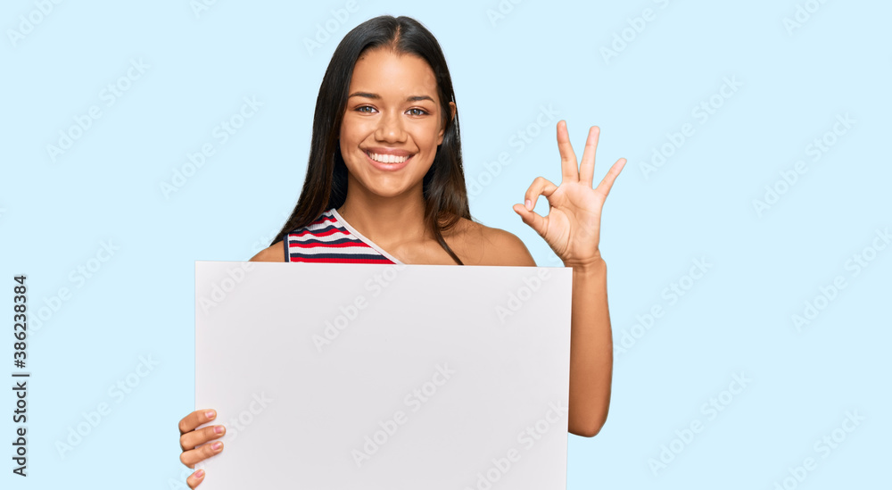 Beautiful hispanic woman holding blank empty banner doing ok sign with fingers, smiling friendly gesturing excellent symbol Beautiful hispanic woman holding blank empty banner doing ok sign with fingers, smiling friendly gesturing excellent symbol