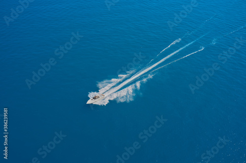 High-speed boat of white color fast motion on blue water in the rays of the sun top view. Top view of a white boat sailing to the blue sea.  Aerial view luxury motor boat. Travel - image.