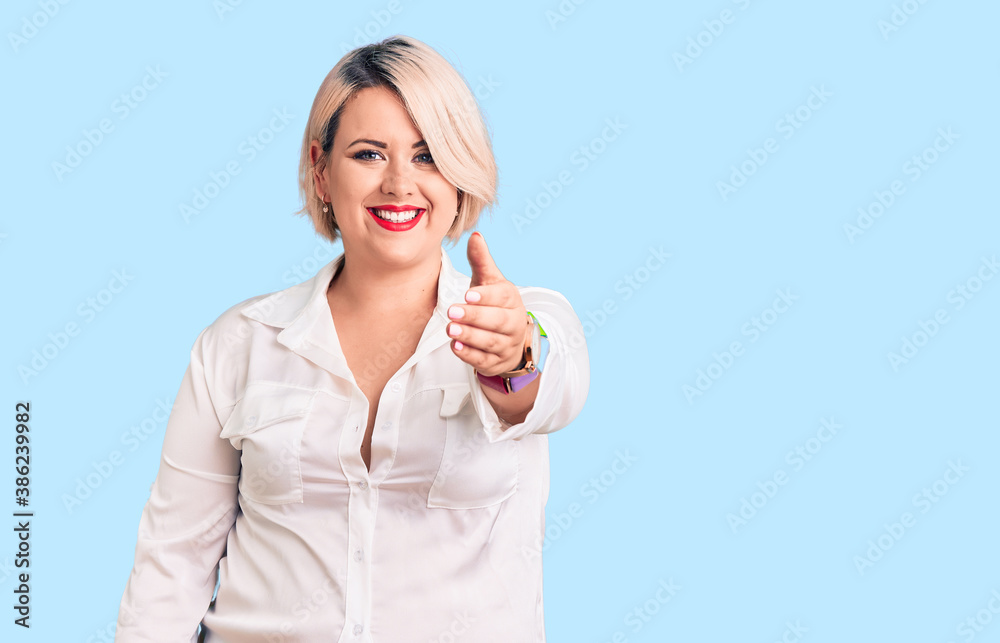 Young blonde plus size woman wearing casual shirt smiling friendly offering handshake as greeting and welcoming. successful business. Young blonde plus size woman wearing casual shirt smiling friendly offering handshake as greeting and welcoming. successful business.