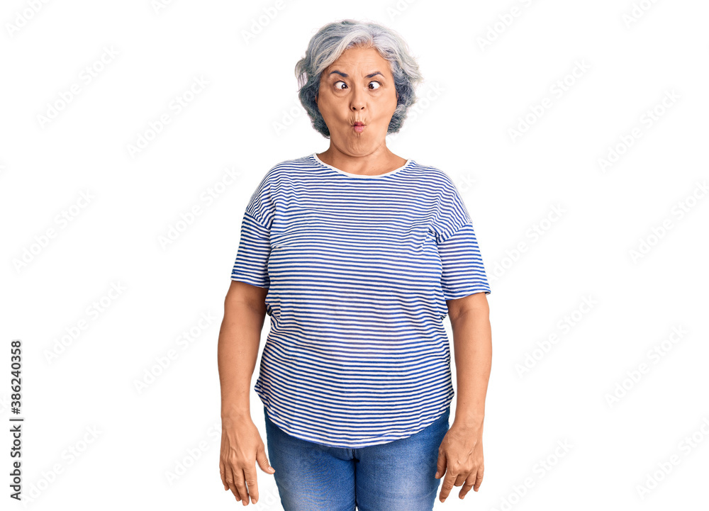 Senior woman with gray hair wearing casual striped clothes making fish face with lips, crazy and comical gesture. funny expression. Senior woman with gray hair wearing casual striped clothes making fish face with lips, crazy and comical gesture. funny expression.
