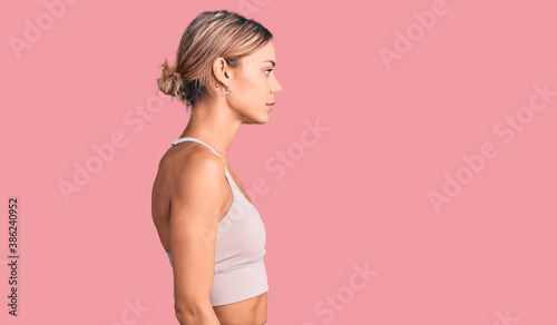 Beautiful caucasian woman wearing sportswear looking to side, relax profile pose with natural face and confident smile.