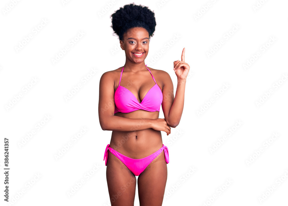 Young african american woman wearing bikini smiling happy pointing with hand and finger to the side Young african american woman wearing bikini smiling happy pointing with hand and finger to the side