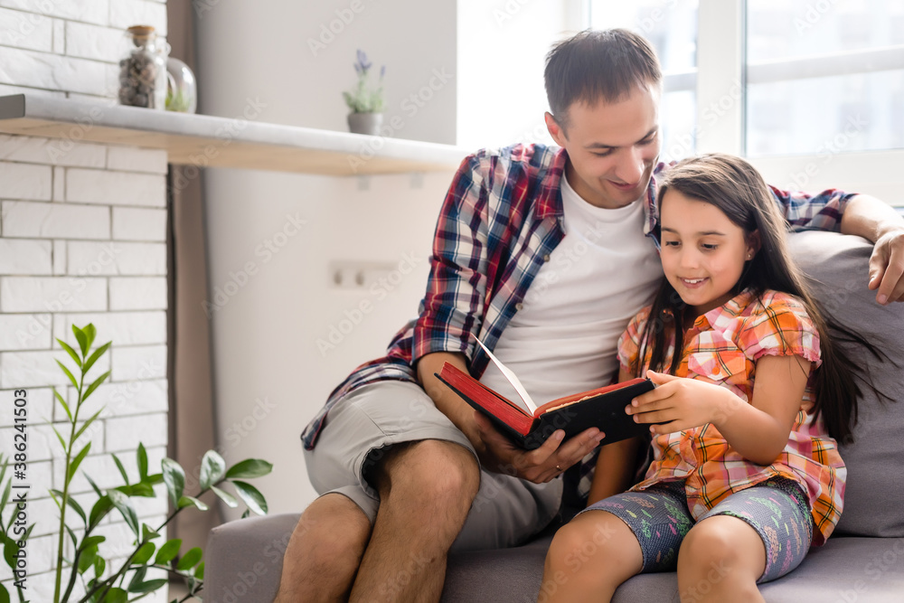 a young father with his little daughter reads the Bible a young father with his little daughter reads the Bible