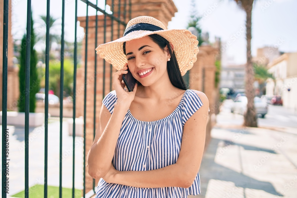 Young latin tourist girl on vacation smiling happy  talking on the smartphone at the city.