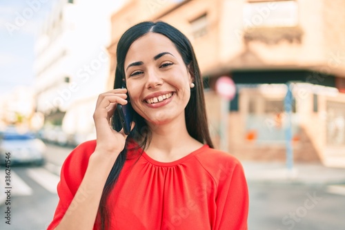 Young latin girl smiling happy talking on the smartphone at the city.